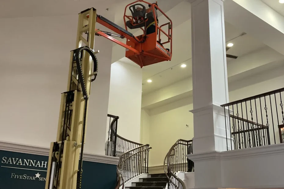 Electrician on a lift inspecting a recessed light fixture to troubleshoot flickering LED bulbs in a Savannah Retirement Community